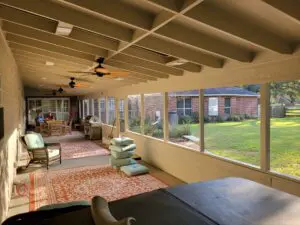 Cozy sunroom with large windows overlooking a green lawn.