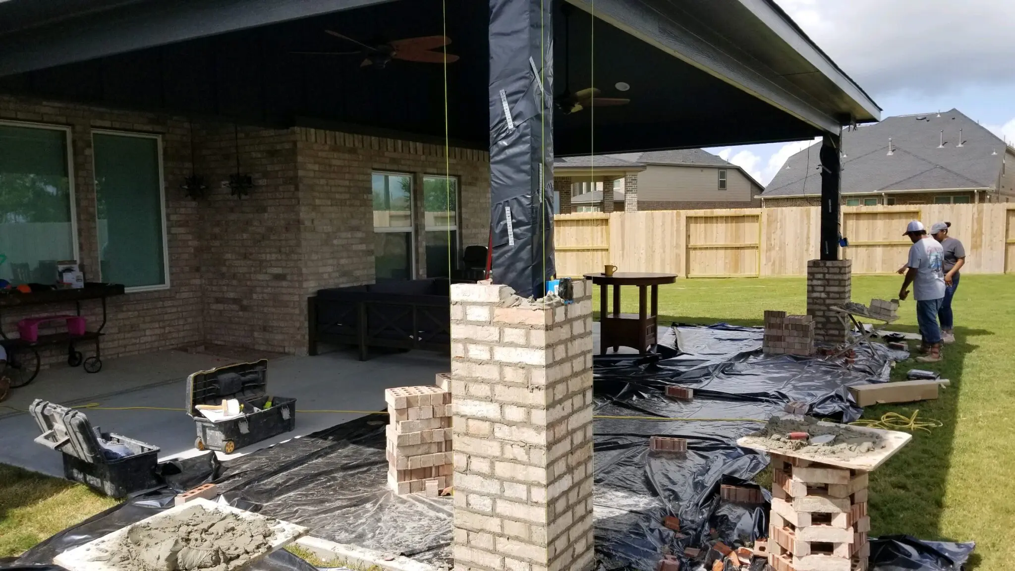 Construction site with brick pillar and covered porch area.