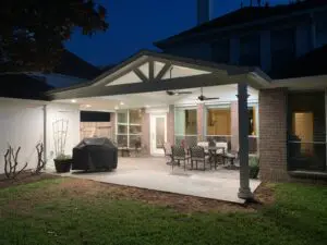 Backyard patio with outdoor dining set and grill illuminated at night.