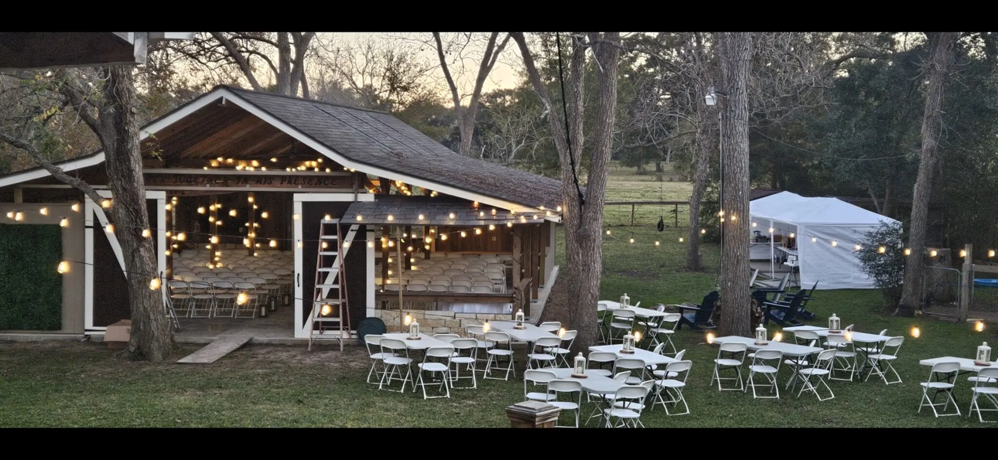 Outdoor wedding reception setup with string lights and round tables.