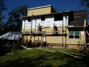 Workers installing siding on house