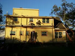 Workers on scaffolding renovating yellow house