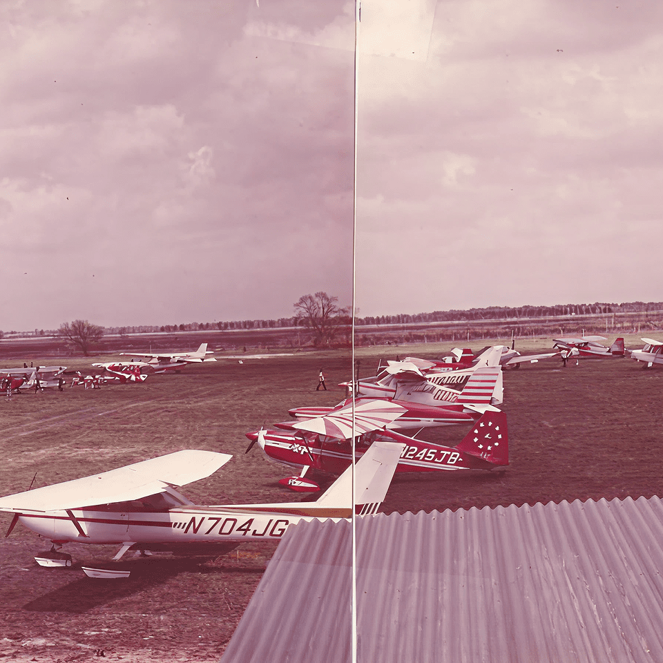 Small airplanes parked on grassy airfield